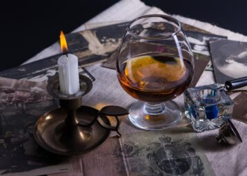 galss of cognac, candle, sitting on a table
