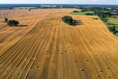 Aerial view of a harvested grain field with hay bales in the European countryside
