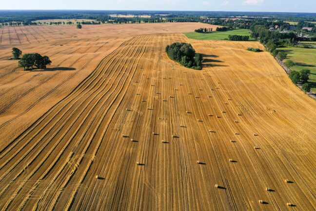 Aerial view of a harvested grain field with hay bales in the European countryside