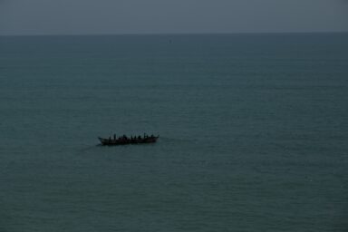 A boat with people silhouetted against a dark sea