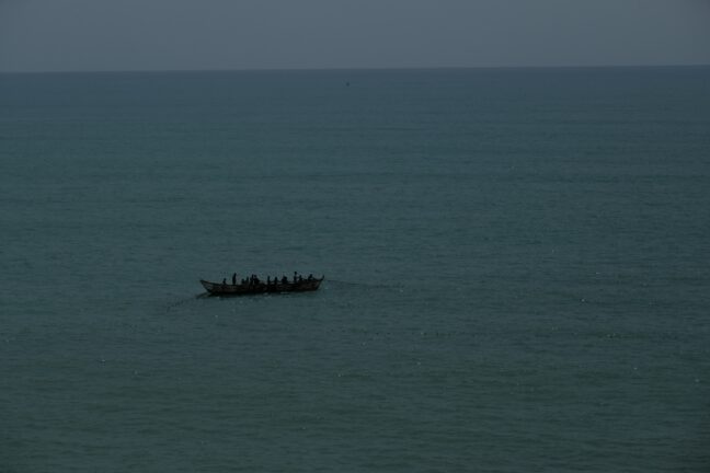 A boat with people silhouetted against a dark sea