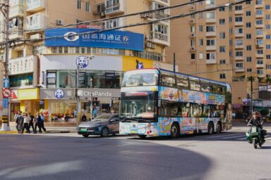 A double-decker bus and electric car on a busy street in China