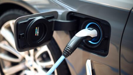 Close-up of an electric vehicle charging connector plugged into a car’s charging port during EV charging