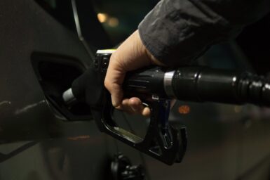 Close-up of a hand inserting a fuel nozzle into a vehicle’s gas tank