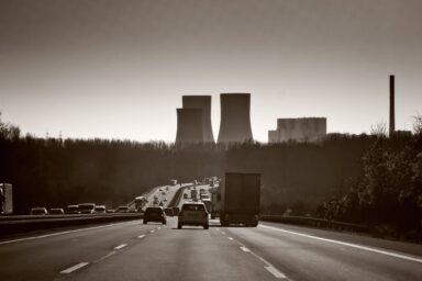 Cars and a truck on a motorway with power plant cooling towers in the background