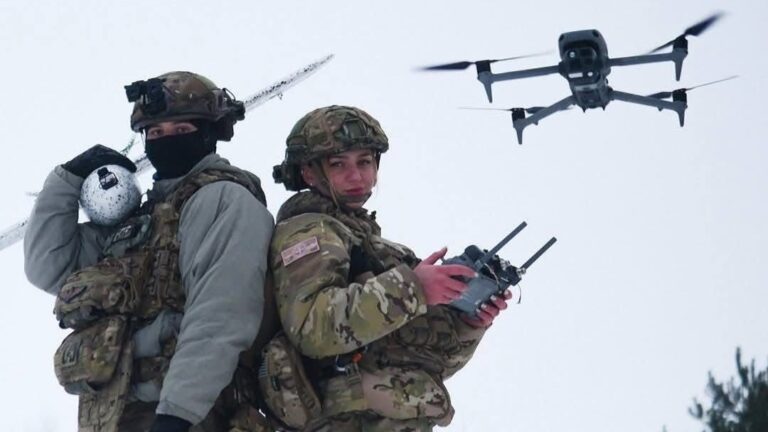 Two Ukrainian drone operators with a drone hovering in the background
