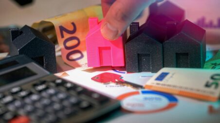 Calculator, euro banknotes and miniature houses symbolising mortgages