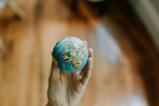 9:15A hand holding a small globe-shaped ball with country outlines