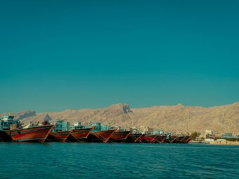 Fishing boats moored in an Iranian port with desert mountains in the background