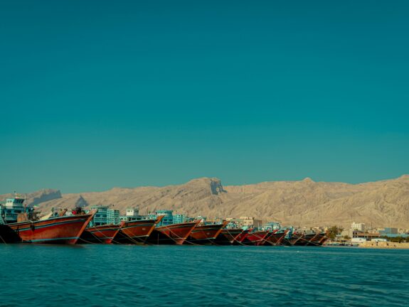 Fishing boats moored in an Iranian port with desert mountains in the background