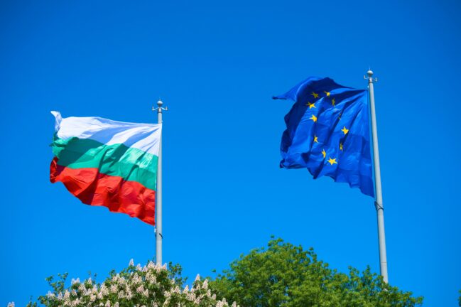 Bulgaria election—Bulgarian and EU flags flying side by side against a blue sky