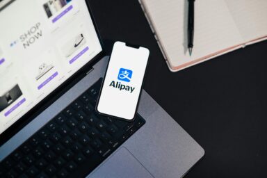 Alipay app on a smartphone next to a laptop
