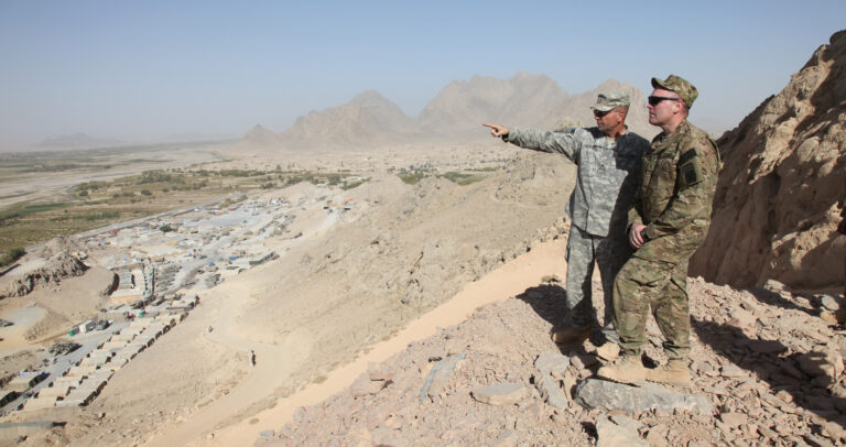 U.S. Army Brig. Gen. Frederick Hodges, left, the outgoing director of operations for U.S. Forces-Afghanistan (USFOR-A) South, discusses the surrounding view with Brig. Gen. Jeffrey Bannister, the incoming director of USFOR-A South, from the top of a mountain at Command Observation Post Masum Ghar, Kandahar province, Afghanistan, Oct. 20, 2010. Hodges and Bannister visited the post to assess area operations and assist with the transfer of authority. / (U.S. Army photo by Cpl. Carol A. Lehman/Released)