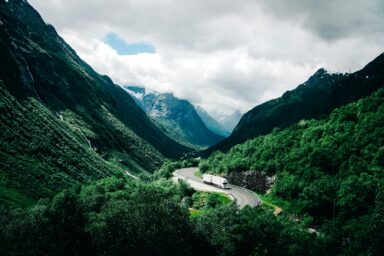 A white truck driving through a mountain valley on a winding road
