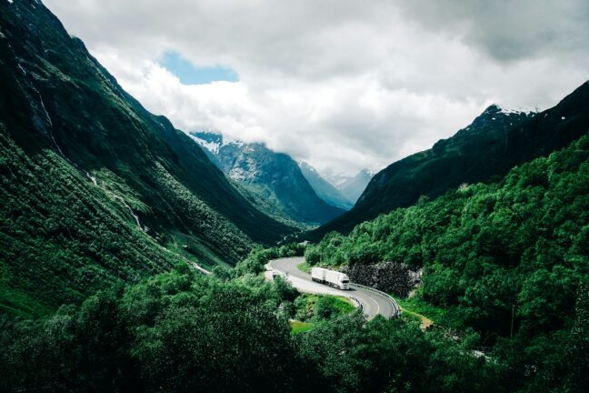 A white truck driving through a mountain valley on a winding road