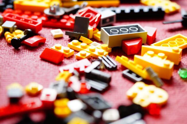 Colourful Lego bricks scattered on a red surface