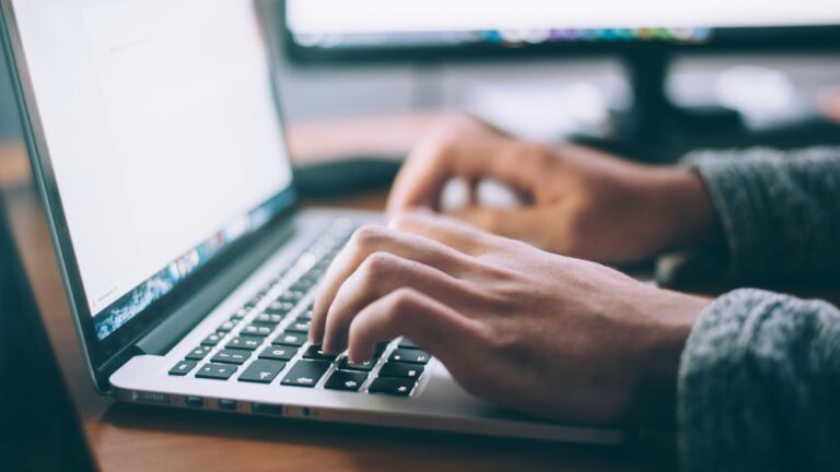 Close-up of hands working on a laptop keyboard