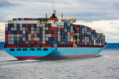 A large Maersk container ship loaded with colourful shipping containers sailing on open water