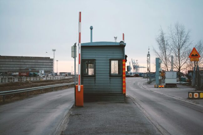An empty border control booth with a raised barrier at a port