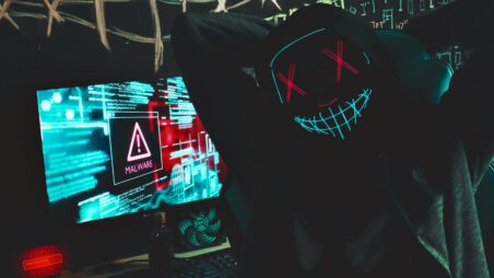Masked hacker uploading malware during a cyberattack