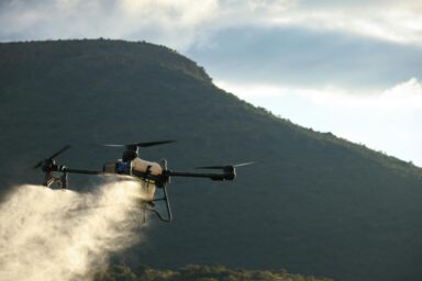 Agricultural drone spraying pesticides in flight