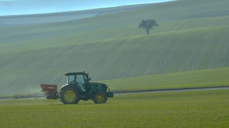Farm tractor spreading fertiliser over a field