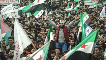 Crowds of Syrian demonstrators waving flags during a public protest