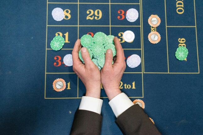 Hands in a suit collecting casino chips on a roulette table