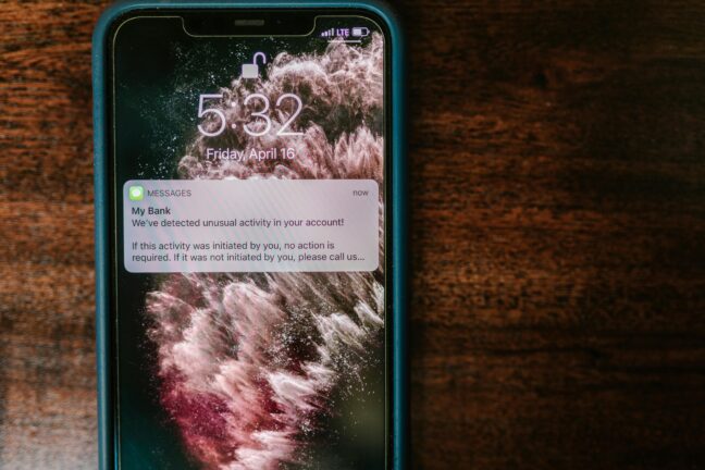 A phone screen showing a fraudulent bank notification warning about unusual account activity