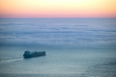 Oil tanker at sea surrounded by low clouds at dawn
