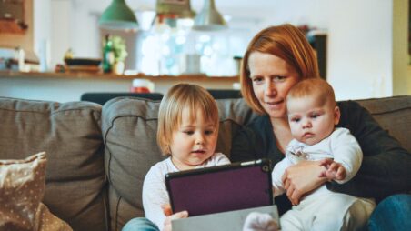 A mother sitting on a couch with two young children