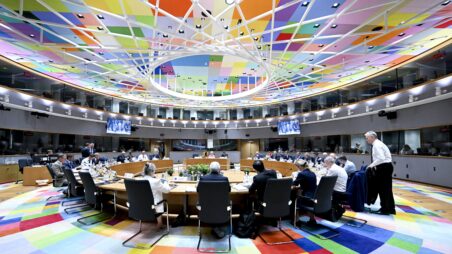 European Council summit roundtable with EU leaders seated beneath a ceiling composed of multicoloured panels