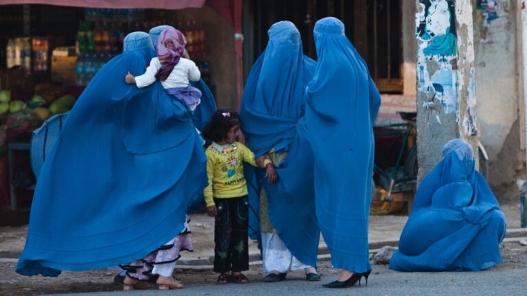 Afghan women in burqas with children on a street in Herat