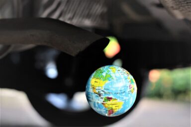 A miniature globe placed under a car exhaust pipe