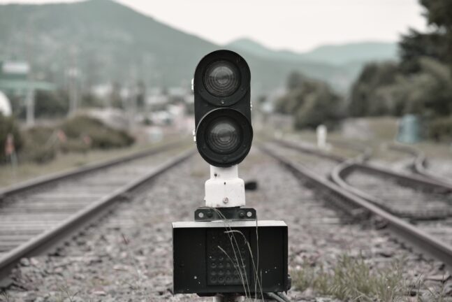 A railway signal standing between two tracks at an old station.
