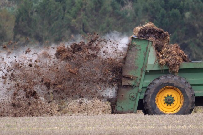 A tractor spreading manure on a field