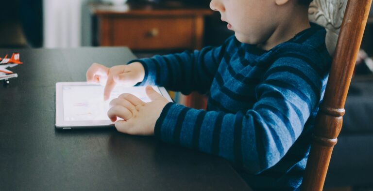 A young child using a tablet at a table.