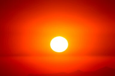 Blazing red sun against an orange sky during a heatwave