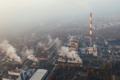 Aerial view of an industrial facility with smokestacks and steam, surrounded by fog