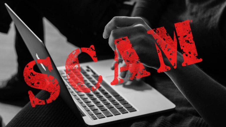 A close-up of a person’s hands working on a laptop, overlaid with a red stamp reading ‘SCAM’