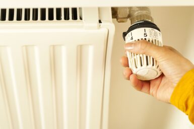 A hand adjusting a radiator thermostat