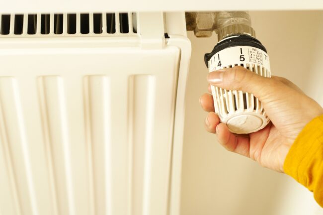 A hand adjusting a radiator thermostat