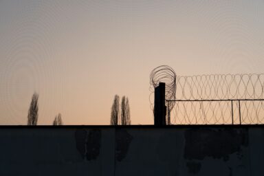 A barbed wire fence silhouetted against a sunset sky