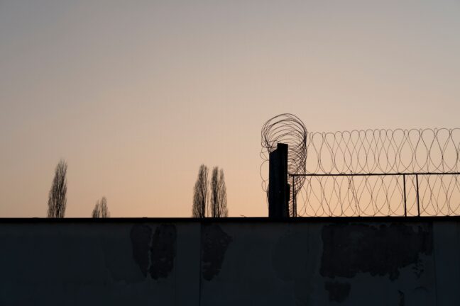 A barbed wire fence silhouetted against a sunset sky