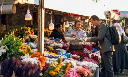 Customers buying flowers at a busy outdoor flower market