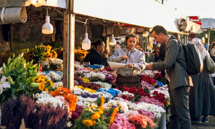 Customers buying flowers at a busy outdoor flower market