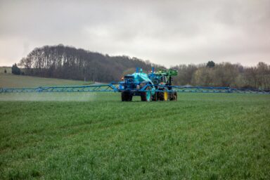 Tractor spraying a green field under an overcast sky