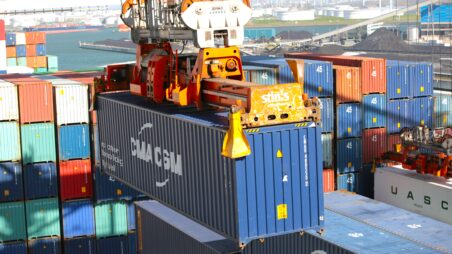 A crane lifts a shipping container at a cargo port