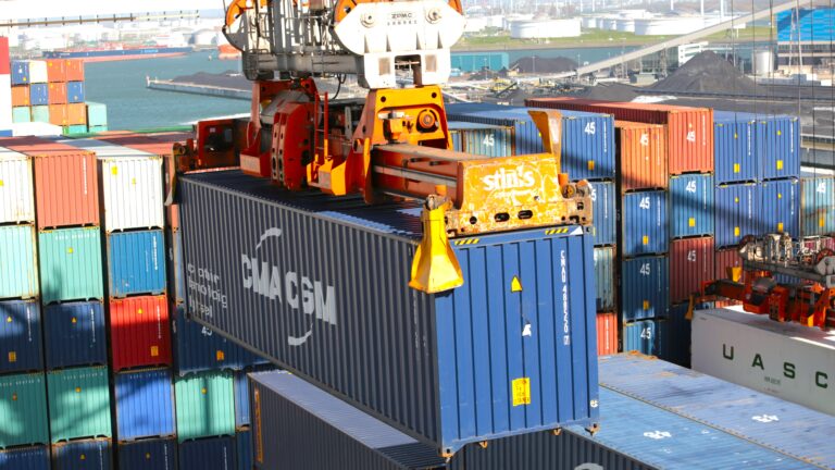 A crane lifts a shipping container at a cargo port