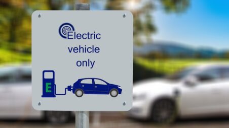 "Electric vehicle only" sign with two electric cars charging in the background